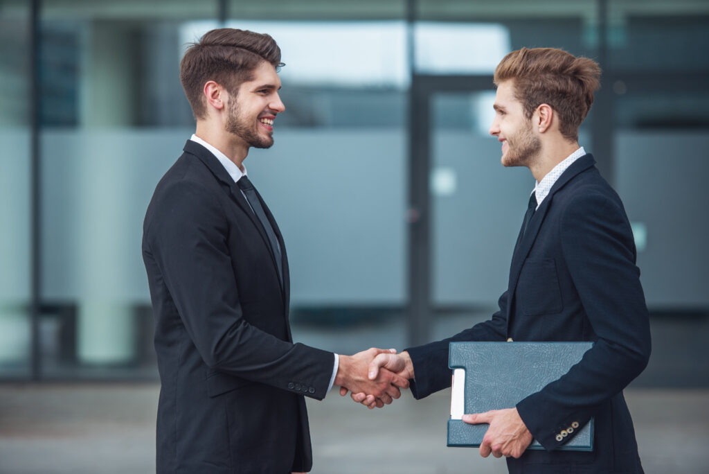 Two field salespeople shaking hands and developing as professionals